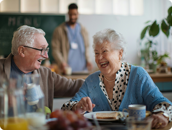 Résidents souriants partageant un repas en établissement